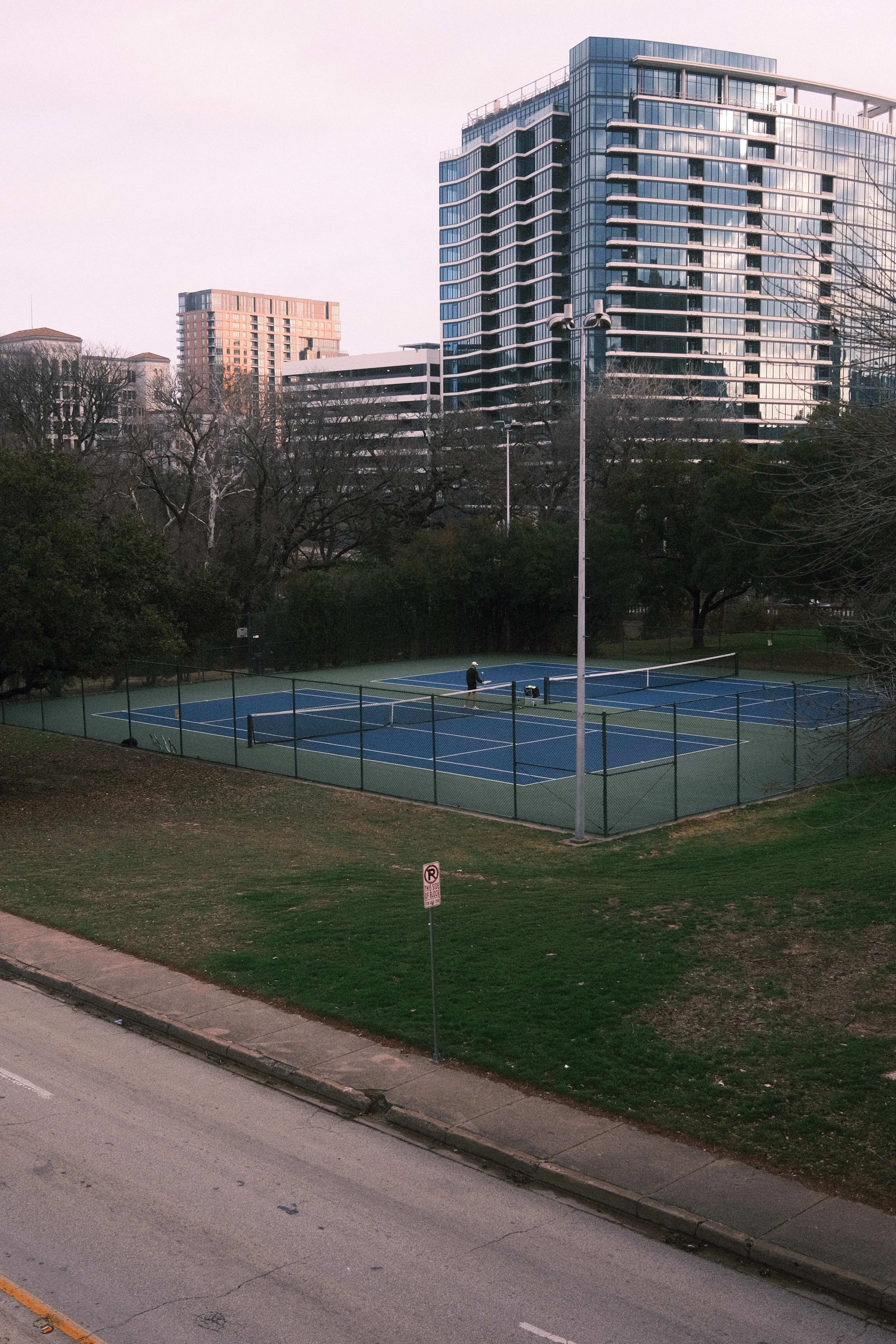Public tennis courts in dallas park with city buildings in background