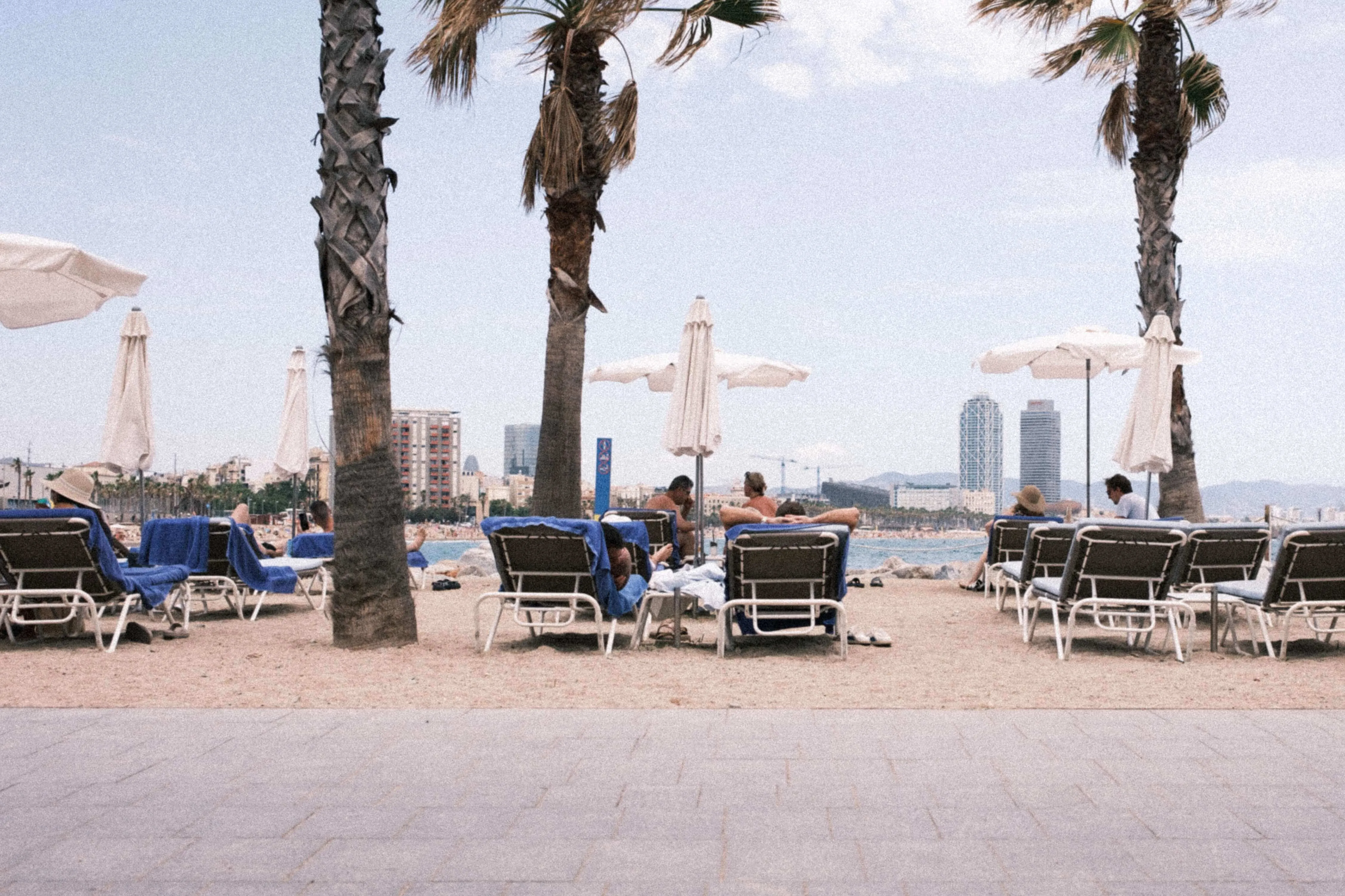 People relaxing on sun loungers at barceloneta beach