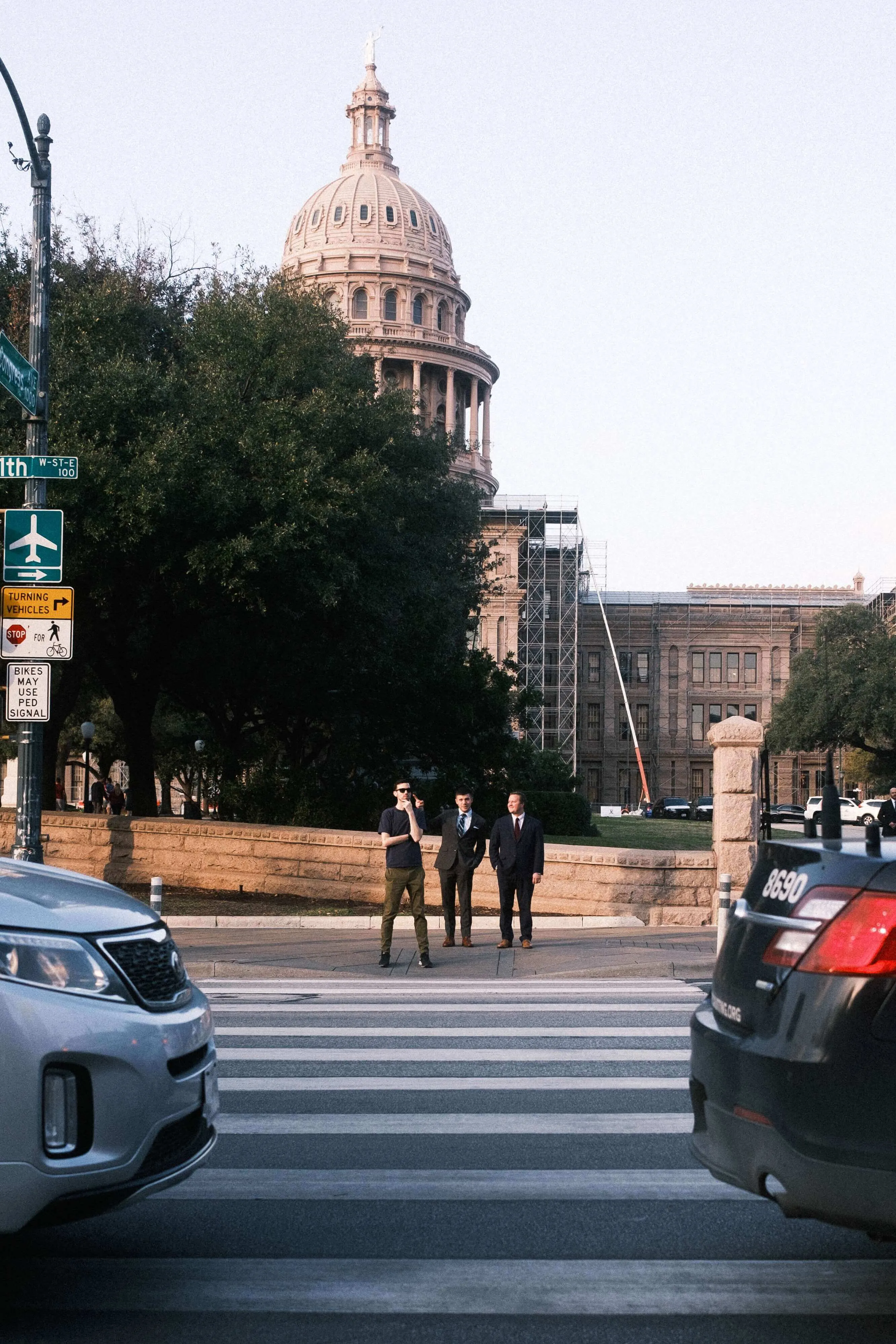 People standing at crosswalk with texas state capitol in background