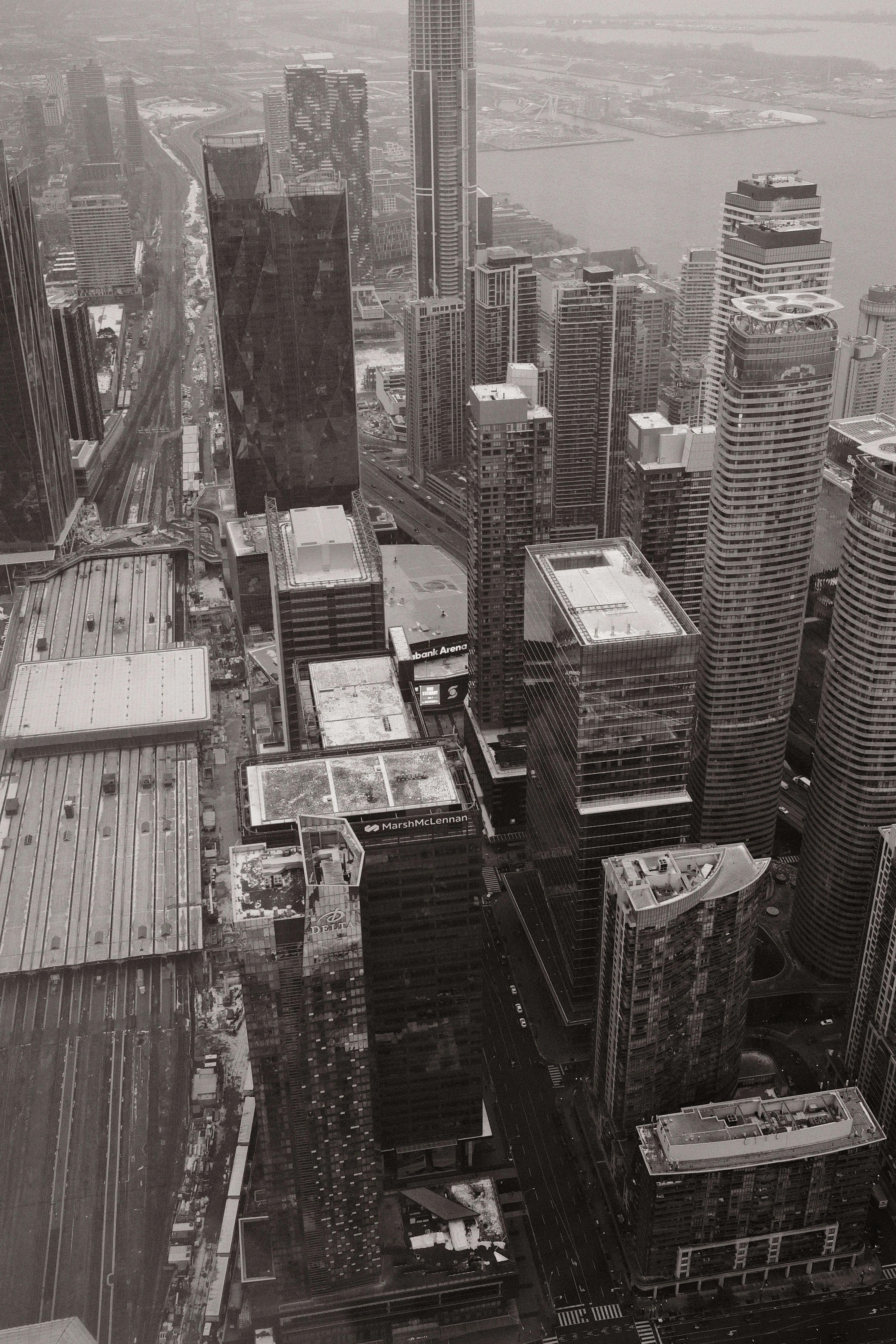 Black and white aerial view of modern downtown skyline with skyscrapers rail lines and waterfront