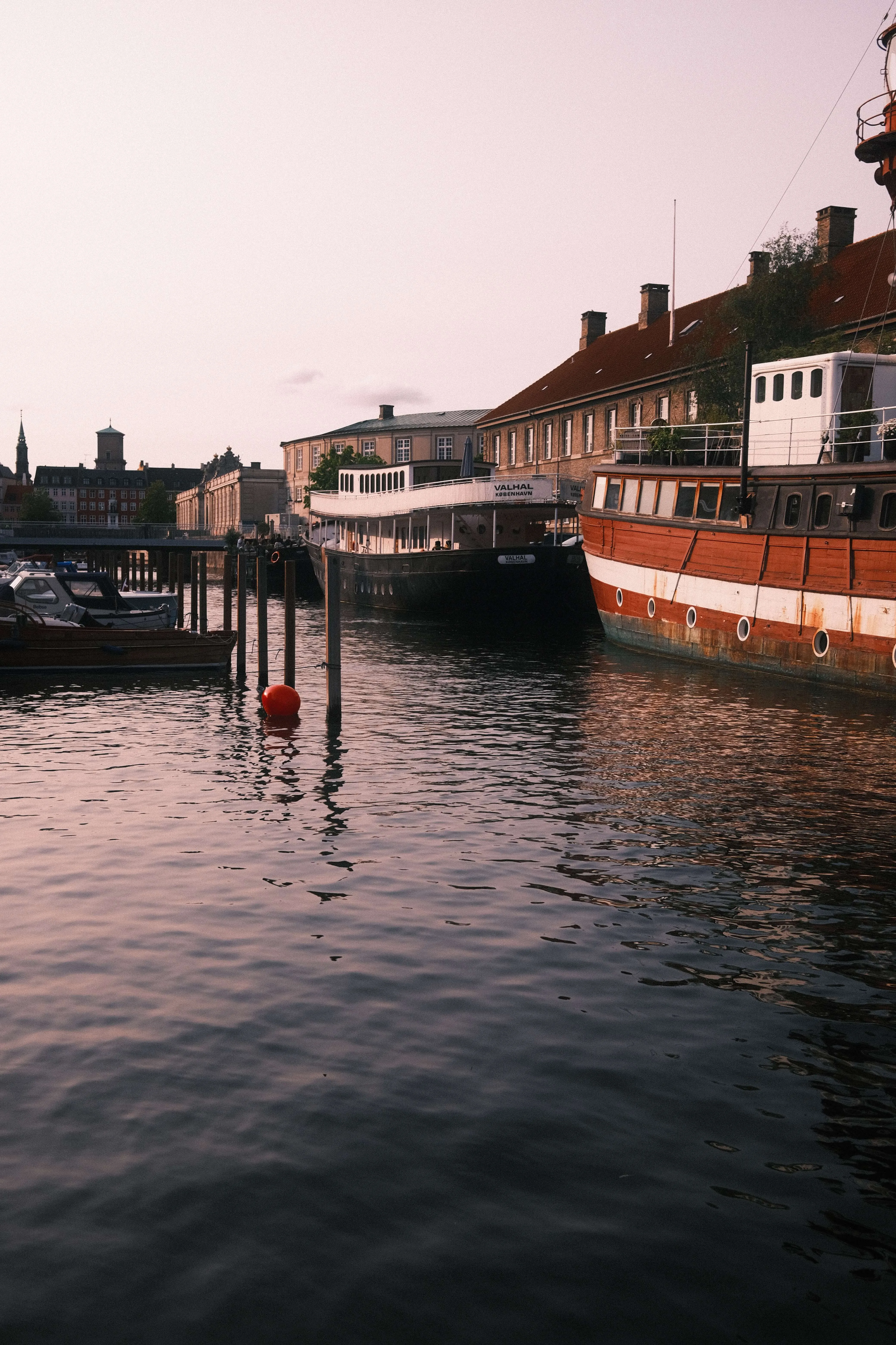 Boats moored in copenhagen harbor at dusk with historic waterfront buildings and calm water