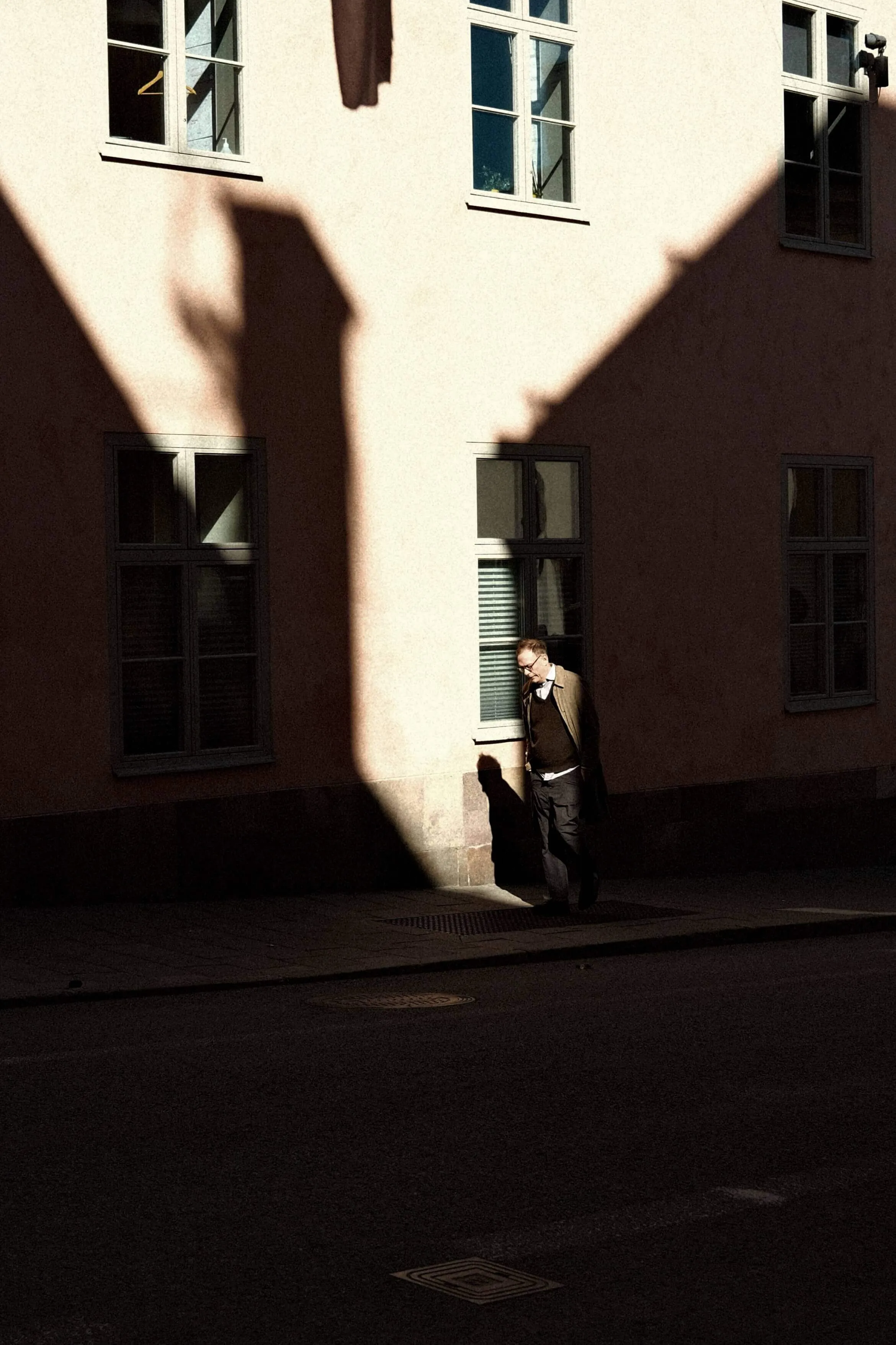 Man walking through sharp building shadow on city wall in stockholm