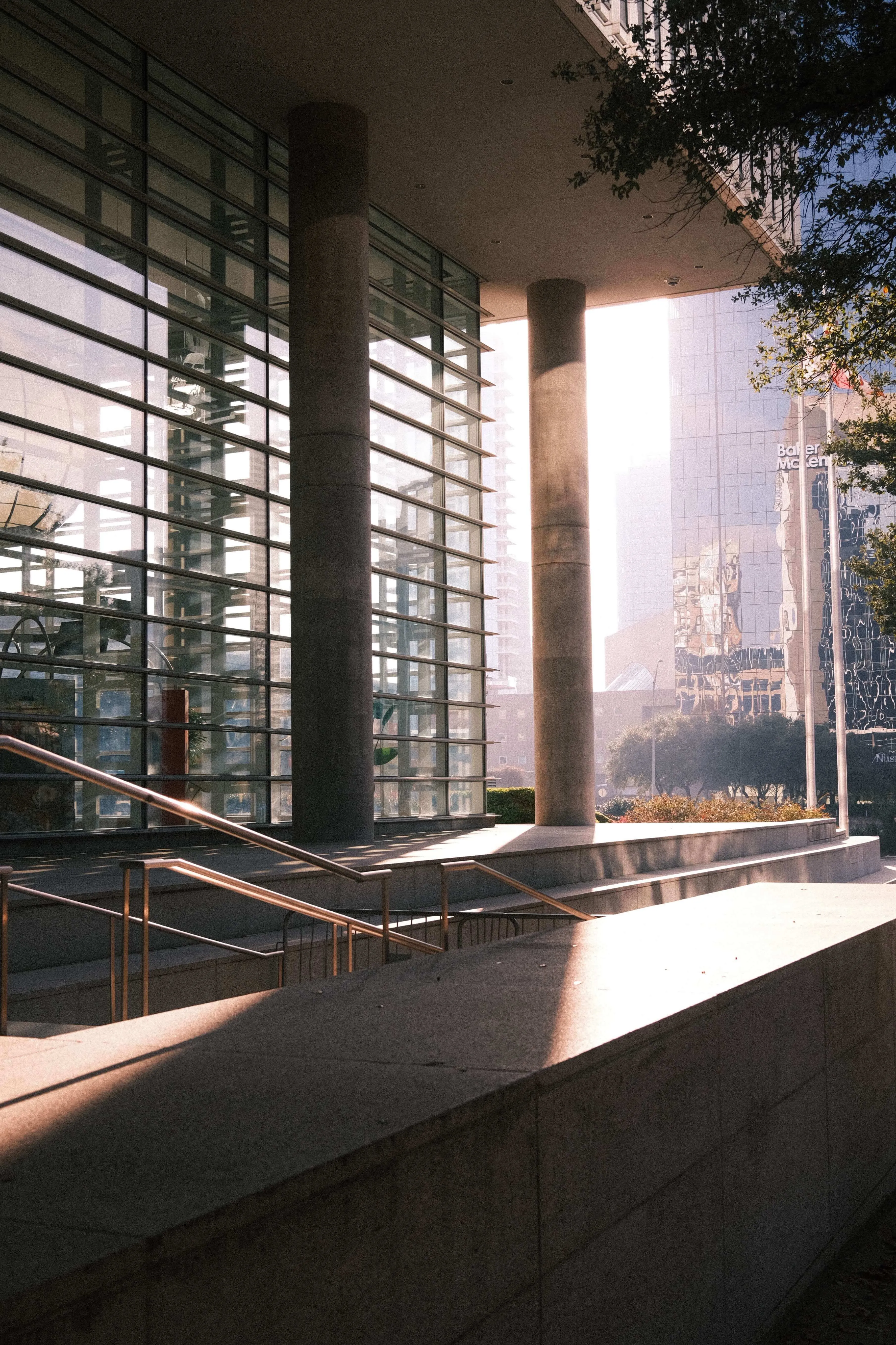 Sunlight streaming through glass building entrance with columns in downtown dallas