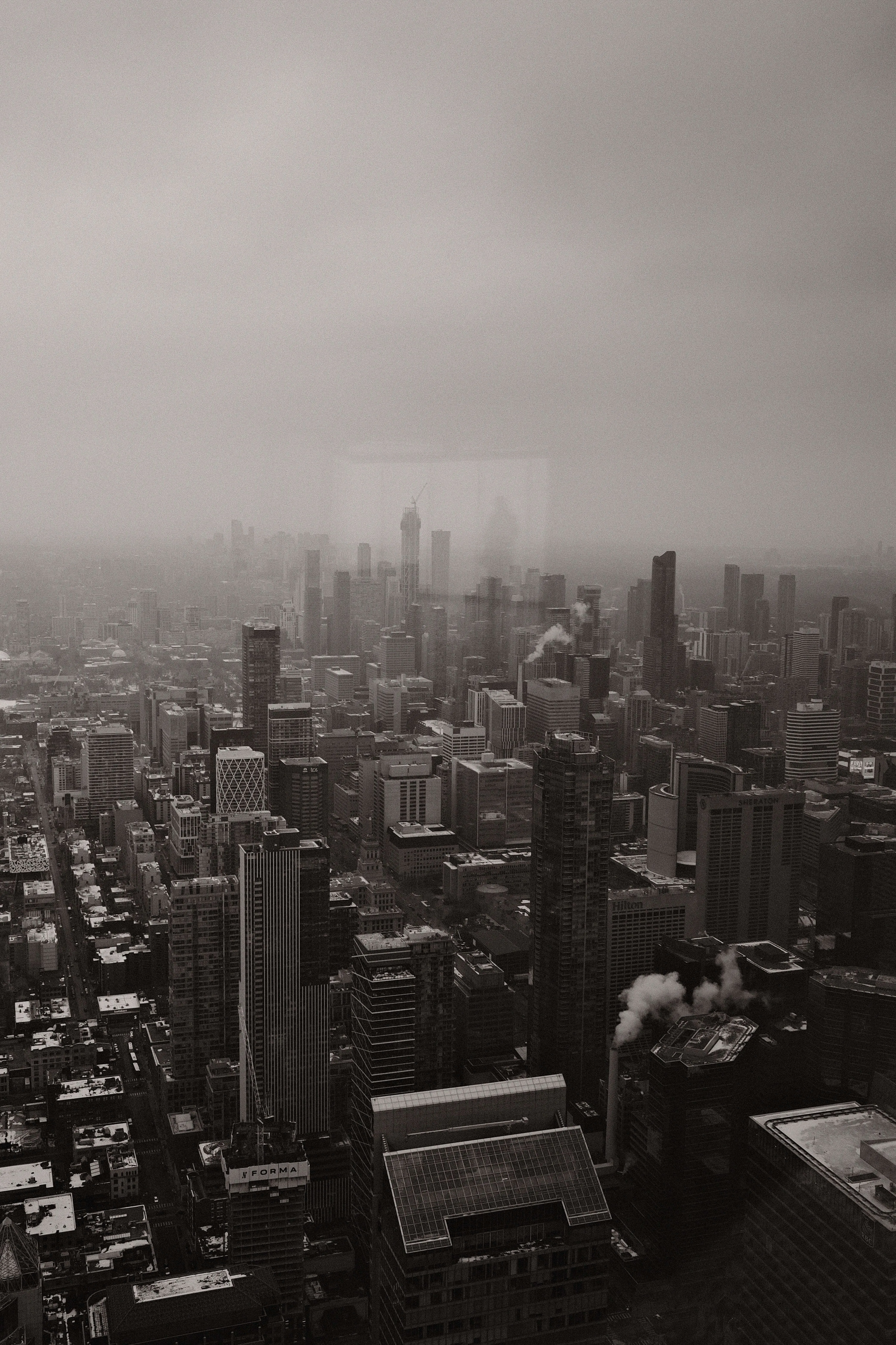 Black and white aerial view of railway corridor cutting through modern city with high rise buildings