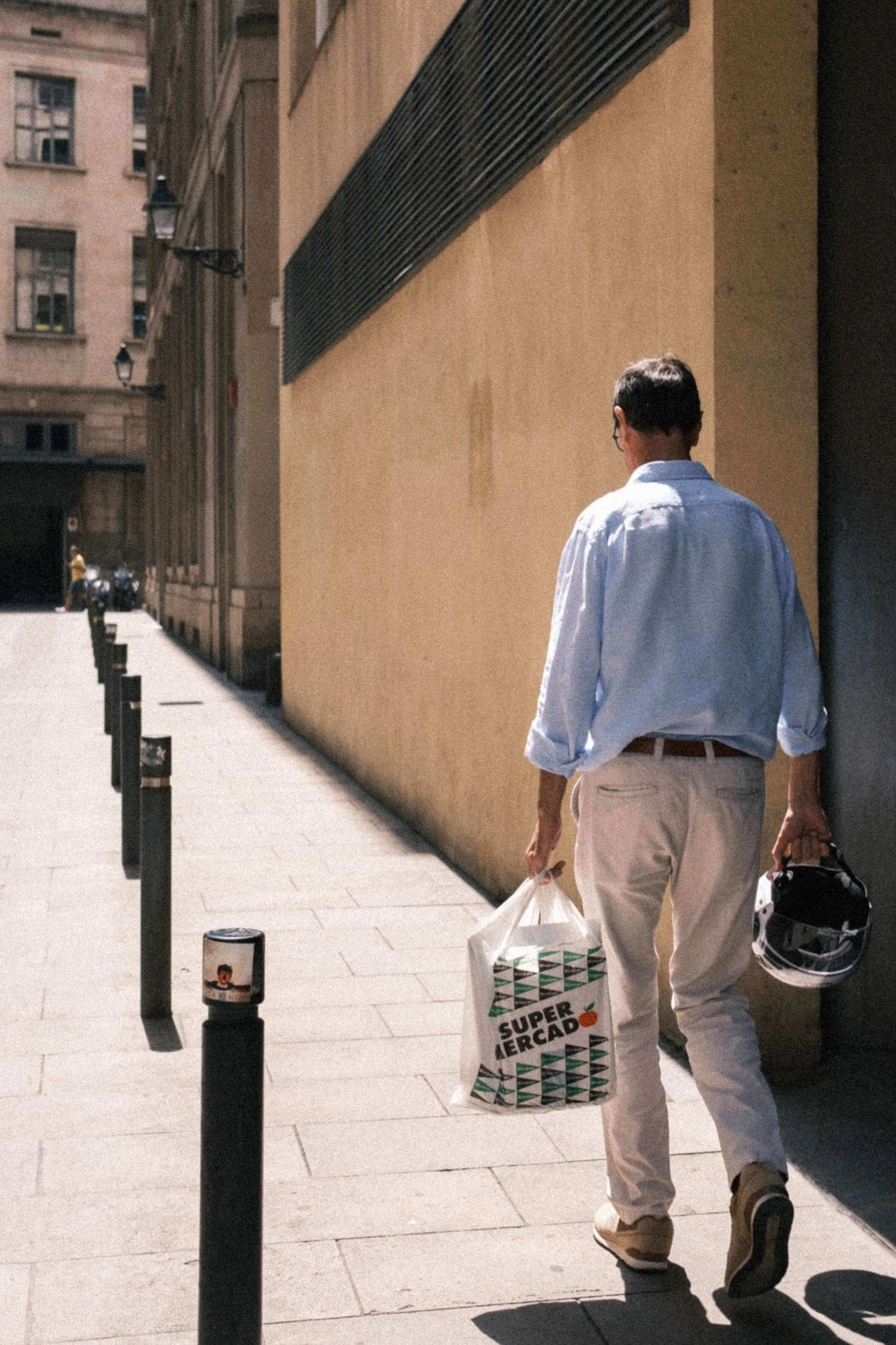 Man carrying long wood plank through narrow barcelona street