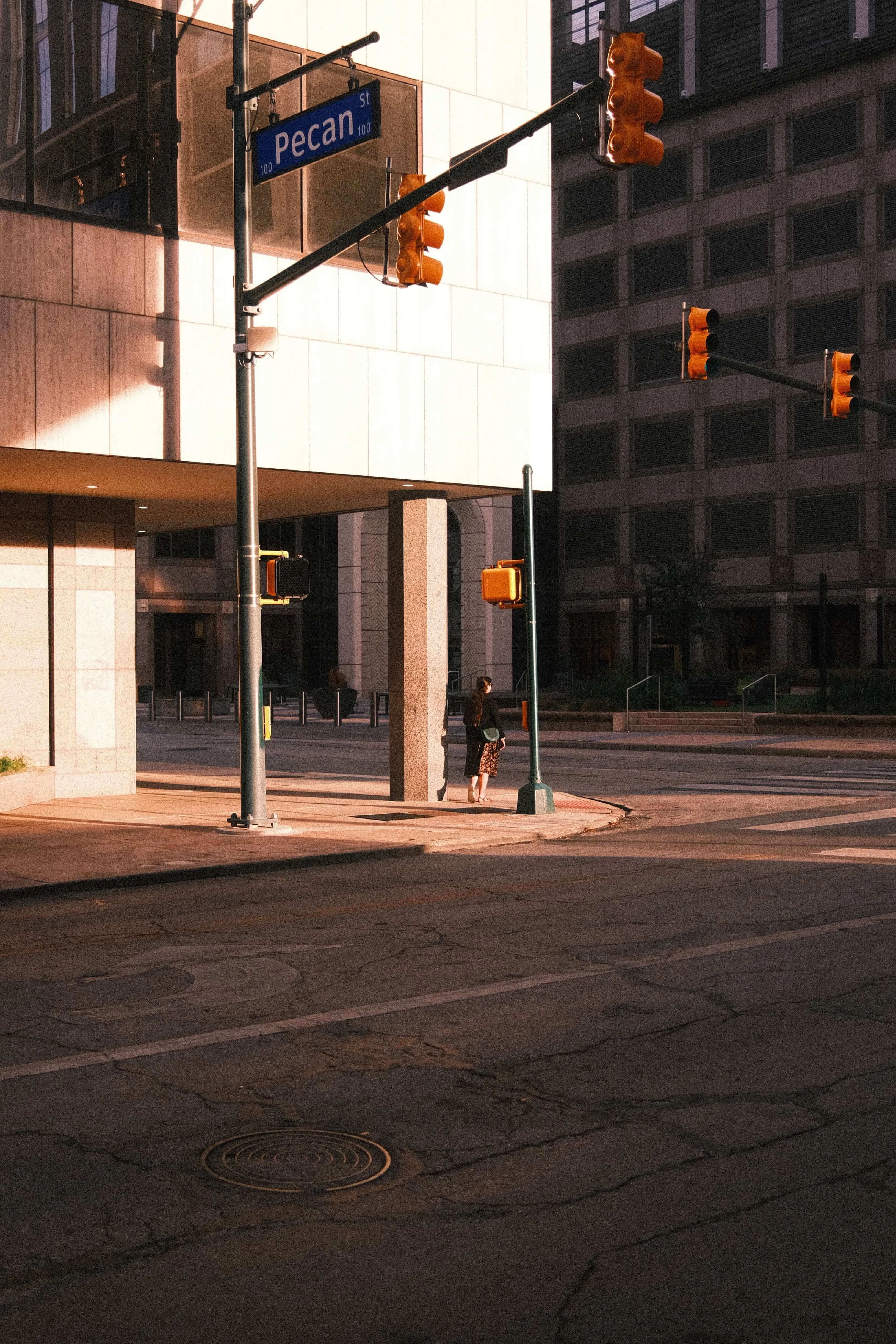 Person waiting at downtown san antonio crosswalk with long afternoon shadows